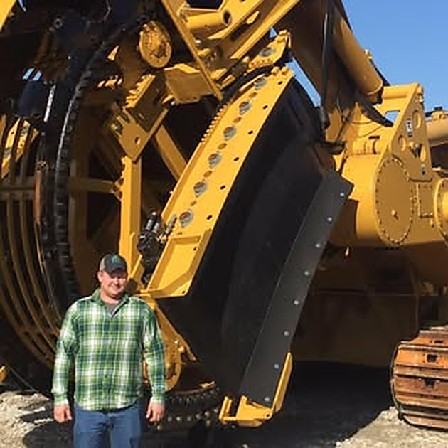 Collin Parks standing beside a large yellow machine