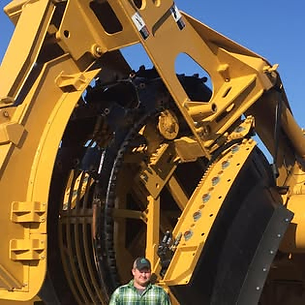 Collin Parks beneath the wheel of a large yellow machine